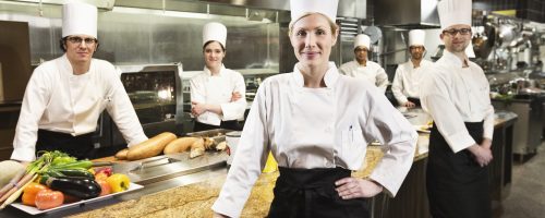 a-portrait-of-a-caucasian-female-chef-and-her-team-of-chefs-in-the-backgroiund-.jpg